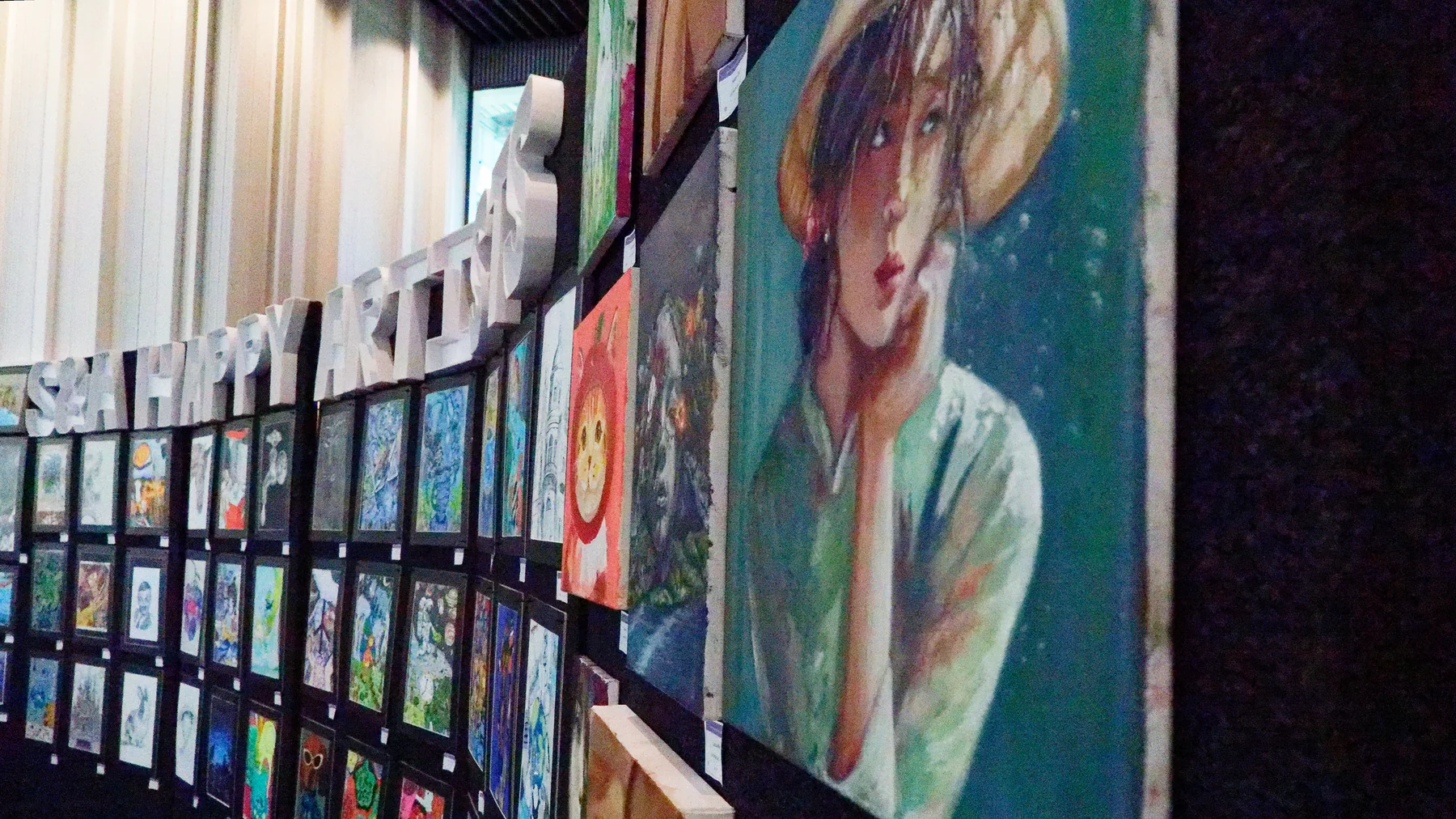 Angled view along a large wall of student artworks at an S&A display